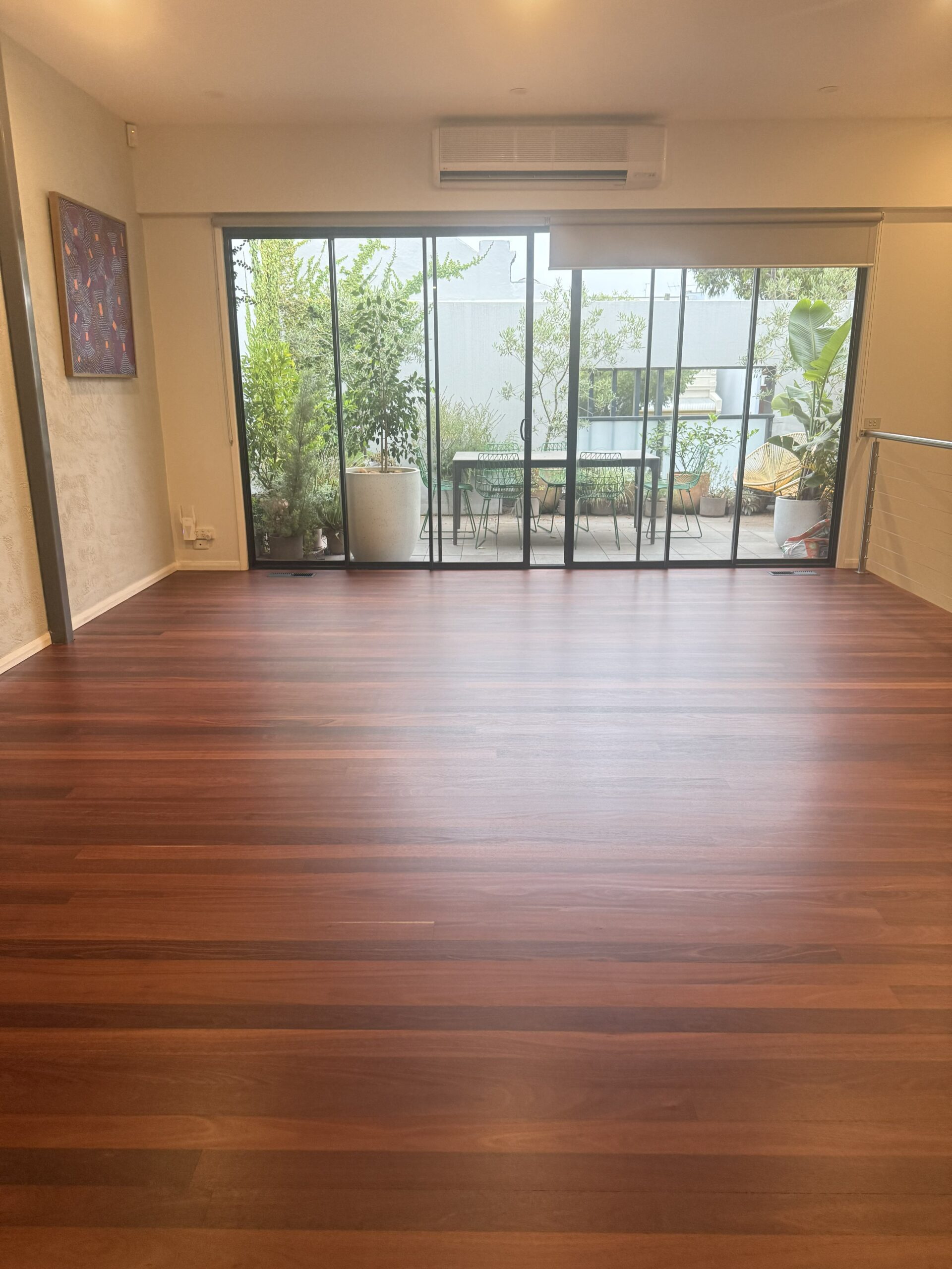 Polished red-toned hardwood timber floor in a living room with courtyard access Melbourne timber flooring by AF Timber Flooring
